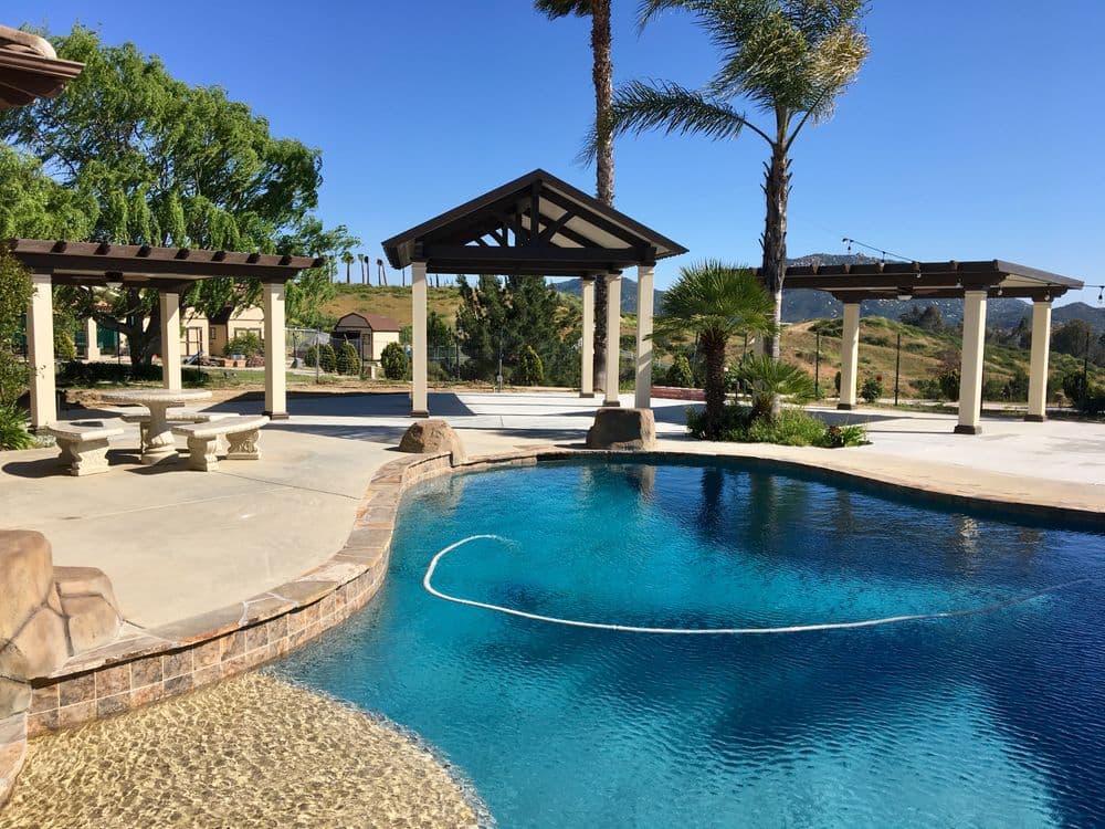 Luxury outdoor pool with seating area and palm trees under clear blue sky.