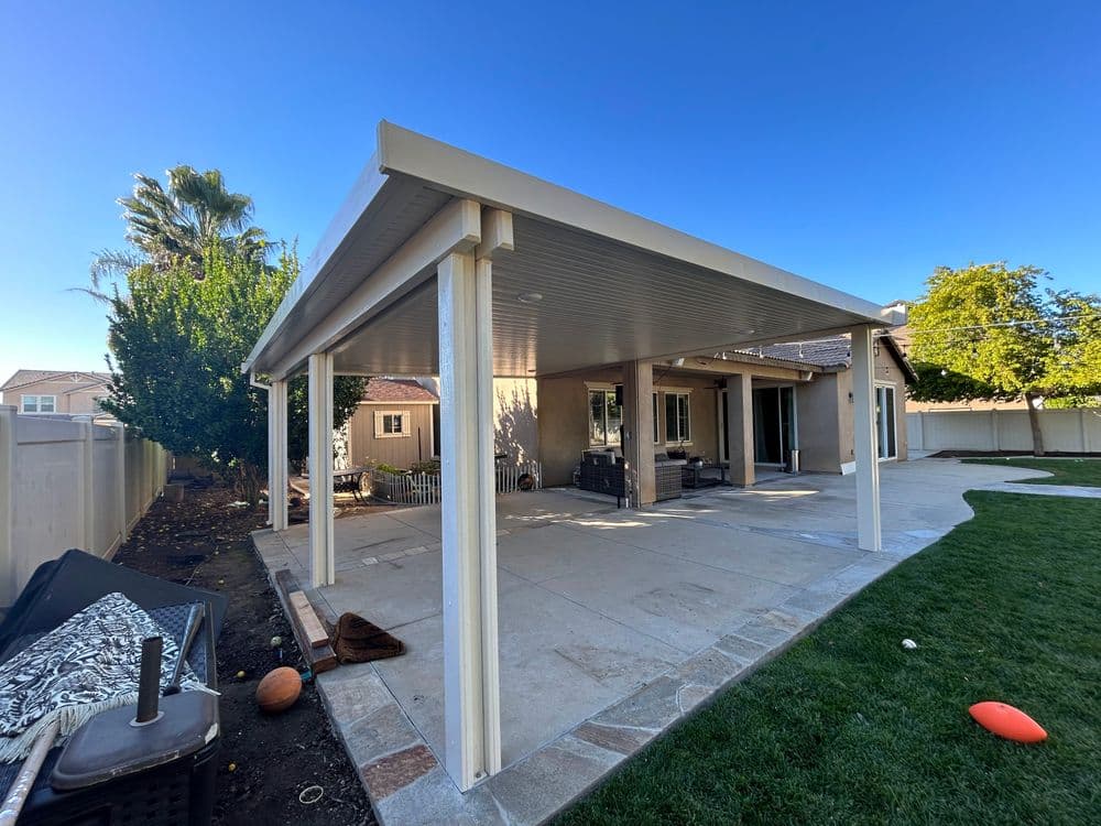 Home patio with a modern cover, grassy area, and landscaped surroundings.
